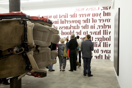 Foreground: Dirk Skreber, Untitled, 2009, car, base plate and pole, approximately 15 x 8 x 7 feet. Background: Sam Durant, Look Back, Wall (St.) Text, 2009, enamel on wall, dimensions variable.